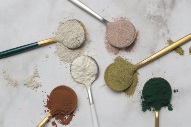 Sağlık ve güzellik için farklı beslenme malzemeleri - kolajen, vitamin, biyotin, kaşıklardaki protein tozu