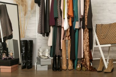 Kadın kıyafetleri ve ayakkabıları. Moda atölyesinde şık ve şık giysilerle elbise askısı. Kaliteli, zamansız moda eserleri.
