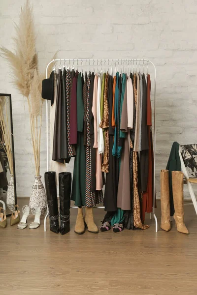 Women\'s clothes and shoes. Clothes rack with stylish and elegant garments in fashion atelier. Good quality timeless fashion pieces.