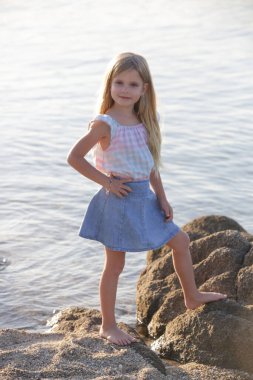 Sevimli 5 yaşında yaşlı bir kız, deniz kenarında eğleniyor.