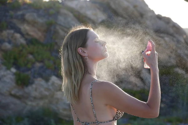 stock image Woman spraying facial mist on her face, summertime skincare concept