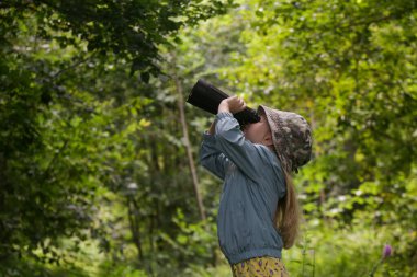 Dürbünle doğayı keşfeden sevimli küçük bir kız. Çocuk dışarıda oynuyor. Çocuklar seyahat, macera ve kuş izleme konsepti.