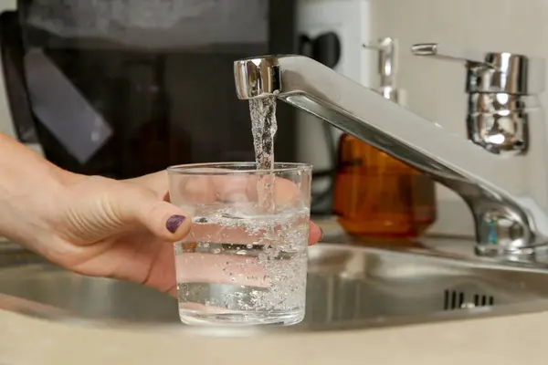 Filling up a glass with fresh drinking water from kitchen faucet