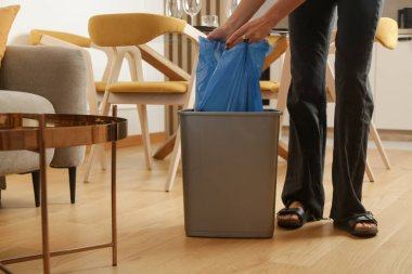 Ev hanımı çöpleri atıyor, evdeki çöp kutusundan plastik çöp torbalarını alıyor.