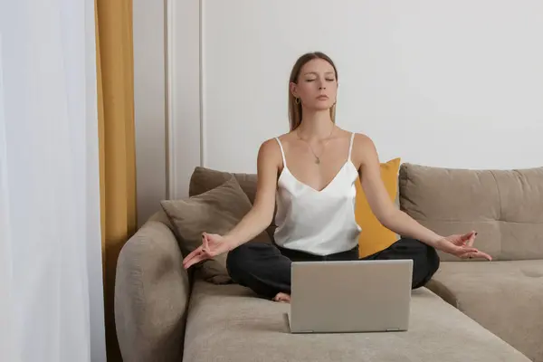 Woman practising meditation on the sofa in the living room, relaxed cosy mindfull lifestyle