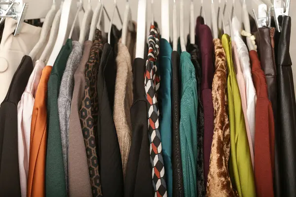 Women\'s fashion. Different clothes on hangers, close up. Huge selection of different used womens clothes on the rack in a second hand shop or thrift store. Concept of waste problem in fashion industry
