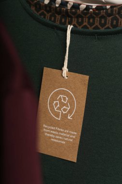 Giysi etiketini geri dönüşüm simgesiyle kapat. Ürün geri dönüşümü kavramı. Sıfır atık, suistainale üretimi, çevre bakımı ve yeniden kullanım kavramı.