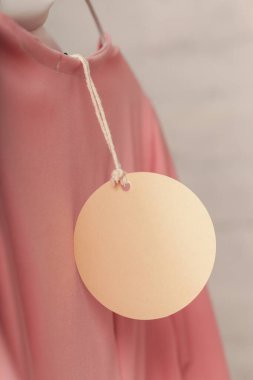 Giyim ürününün fiyat etiketini kapat. Boş yuvarlak etiketli bir kıyafet modeli. Moda endüstrisi ve perakende konsepti.