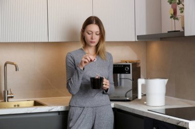 Genç bayan mutfakta bir fincan çayla