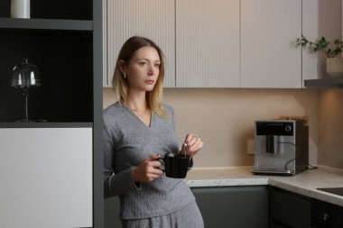 Genç bayan mutfakta bir fincan çayla