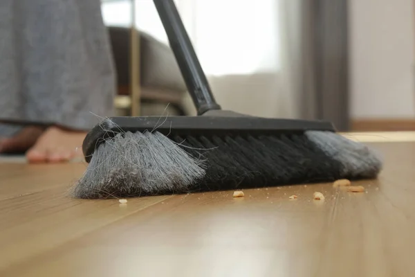 Home cleaning. Close up of woman doing housework, holding a broom and sweeping floor