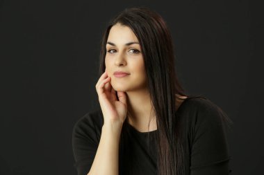 Siyah elbiseli, uzun kahverengi saçlı, doğal güzel bir kadının stüdyo portresi.