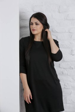 Siyah elbiseli, uzun kahverengi saçlı, doğal güzel bir kadının stüdyo portresi.