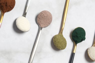 Sağlık ve güzellik için farklı beslenme malzemeleri - kolajen, vitamin, biyotin, kaşıklardaki protein tozu