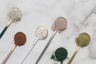 Sağlık ve güzellik için farklı beslenme malzemeleri - kolajen, vitamin, biyotin, kaşıklardaki protein tozu