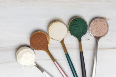 Sağlık ve güzellik için farklı beslenme malzemeleri - kolajen, vitamin, biyotin, kaşıklardaki protein tozu