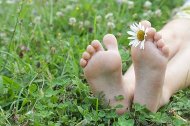 Yeşil çimenlerin üzerinde çocuk ayakları, çayır üzerinde yalın ayak küçük kız, kırsal yaşam tarzı, topraklama ve doğayla bağ kurma kavramı