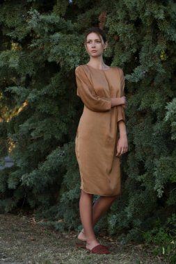 Altın sarısı ipek elbiseli güzel genç manken, moda yaz portresi, zarif lüks kadın tarzı.