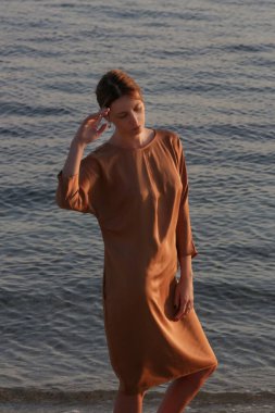 Altın sarısı ipek elbiseli güzel genç manken, moda yaz portresi, zarif lüks kadın tarzı.