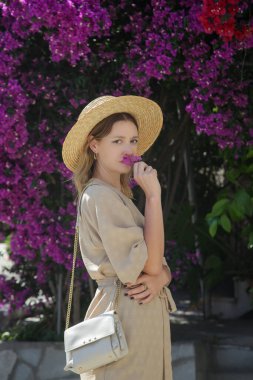 Yunan adasında yaz tatili boyunca bej keten elbiseli ve hasır şapkalı güzel bir turist portresi.