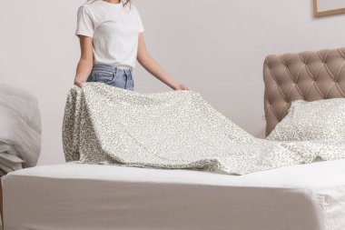 Yatak odasında çarşaf değiştiren kadın, rahat ev hayatı, ev hanımı temizliği, yatak odası düzenleme, ev işi konsepti..