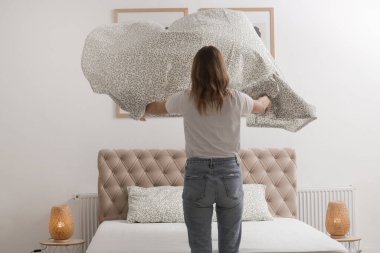 Yatak odasında çarşaf değiştiren kadın, rahat ev hayatı, ev hanımı temizliği, yatak odası düzenleme, ev işi konsepti..