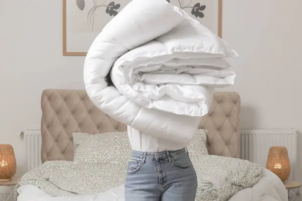 柔らかい白い折り畳まれた羽毛布団と枕の山を彼女の寝室 居心地の良い家庭生活 主婦のクリーニング 寝室の整頓 家事のコアコンセプト ストック画像