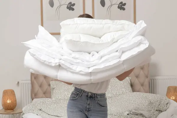 柔らかい白い折り畳まれた羽毛布団と枕の山を彼女の寝室 居心地の良い家庭生活 主婦のクリーニング 寝室の整頓 家事のコアコンセプト ストックフォト