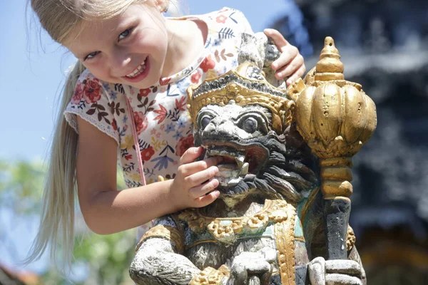 Endonezya 'nın Bali kentindeki bir sokak tapınağında geleneksel Bali heykeli olan genç bir kızın açık hava portresi.