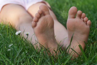 Yeşil çimenlerin üzerinde çocuk ayakları, çayır üzerinde yalın ayak küçük kız, kırsal yaşam tarzı, topraklama ve doğayla bağ kurma kavramı