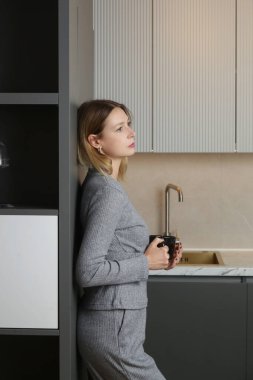 Genç bayan mutfakta bir fincan çayla