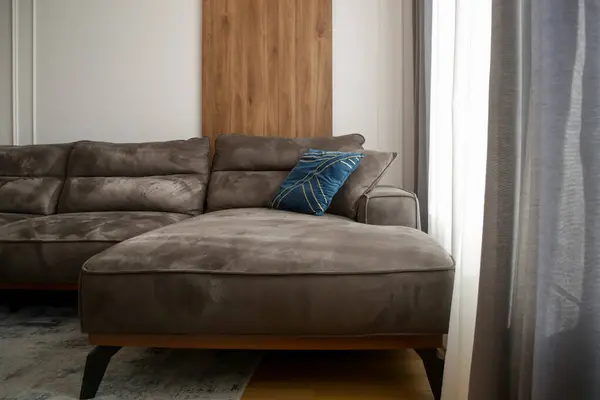 Grey comfortable sofa with blue cushion next to the big window with lot of natural sunlights