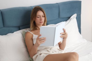Güzel genç kadın yatakta bir kitap okuma