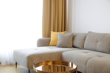 Gri rahat kanepe, hardal sarısı yastık, perdeler ve sehpa, modern yaşam konsepti..