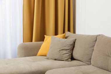 Gri rahat kanepe, hardal sarısı yastık, perdeler ve sehpa, modern yaşam konsepti..