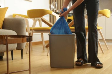 Ev hanımı çöpleri atıyor, evdeki çöp kutusundan plastik çöp torbalarını alıyor.