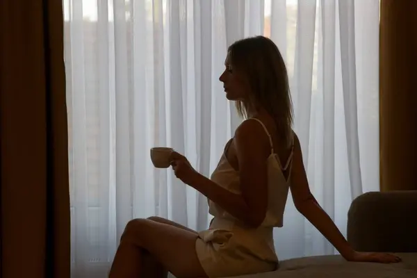 Woman drinking coffee next to the window
