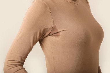  Bej pamuklu balıkçı yaka kazaklı, koltuk altında terli bir kadın resmi.