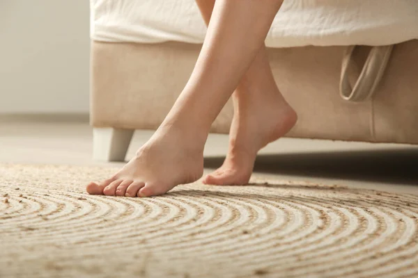 Barefoot woman\'s feet on the floor next to bed in the morning in her home or hotel
