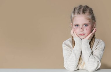 Yüzünde boxer örgüleri ve parıltıları olan sevimli sarışın bir kızın portresi.