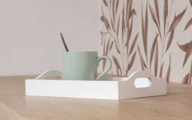 Mutfaktaki ahşap tepside yeşil seramik çay kupası.