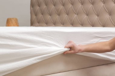 Yatak çarşaflarını değiştiriyorum. Kadın yatağı toplarken beyaz pamuklu çarşaf giyiyor..