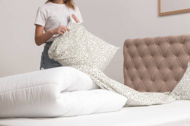 Yatak odasında çarşaf değiştiren kadın, rahat ev hayatı, ev hanımı temizliği, yatak odası düzenleme, ev işi konsepti..