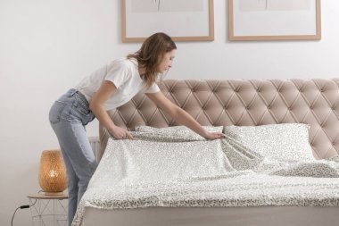 Yatak odasında çarşaf değiştiren kadın, rahat ev hayatı, ev hanımı temizliği, yatak odası düzenleme, ev işi konsepti..