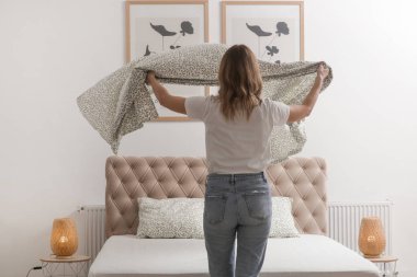 Yatak odasında çarşaf değiştiren kadın, rahat ev hayatı, ev hanımı temizliği, yatak odası düzenleme, ev işi konsepti..