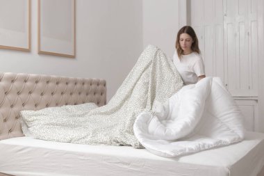 Yatak odasında çarşaf değiştiren kadın, rahat ev hayatı, ev hanımı temizliği, yatak odası düzenleme, ev işi konsepti..