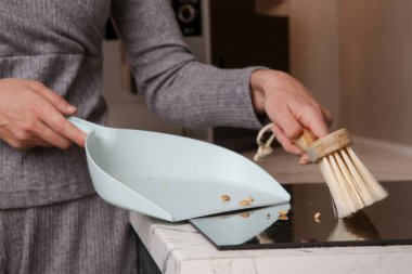 Küçük süpürge ve faraşla apartman dairesini temizleyen kadının ellerini kapat.