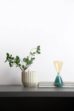 Ev dekorasyonu - Modern kum saati ve ev bitkisi oturma odasındaki rafta..