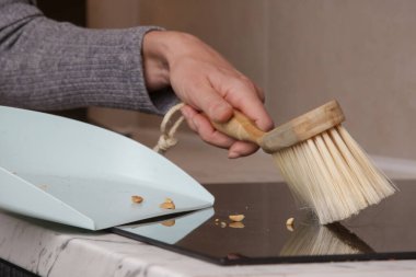 Küçük süpürge ve faraşla apartman dairesini temizleyen kadının ellerini kapat.