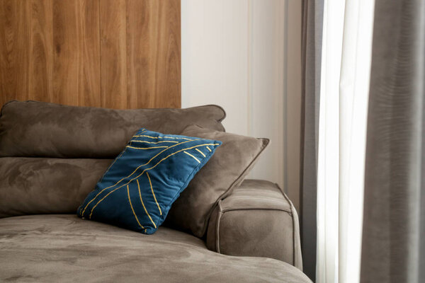 Grey comfortable sofa with blue cushion next to the big window with lot of natural sunlights